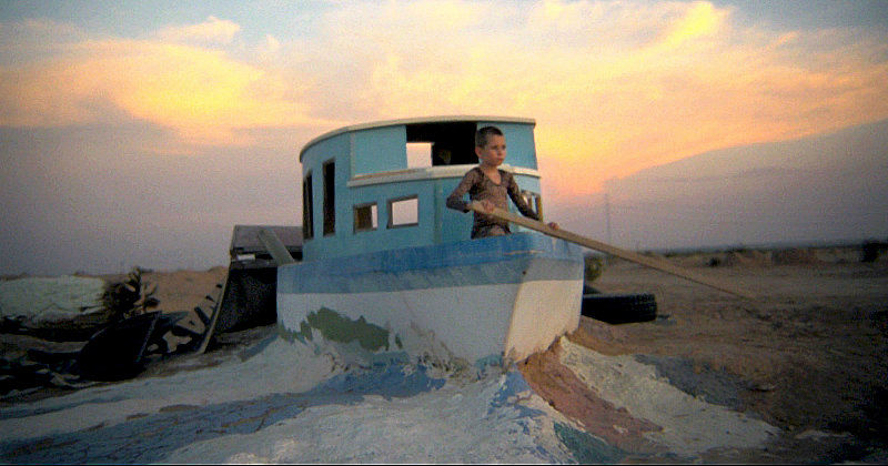 Pojke i båt på stranden i dokumentären Bombay Beach i SVT Play