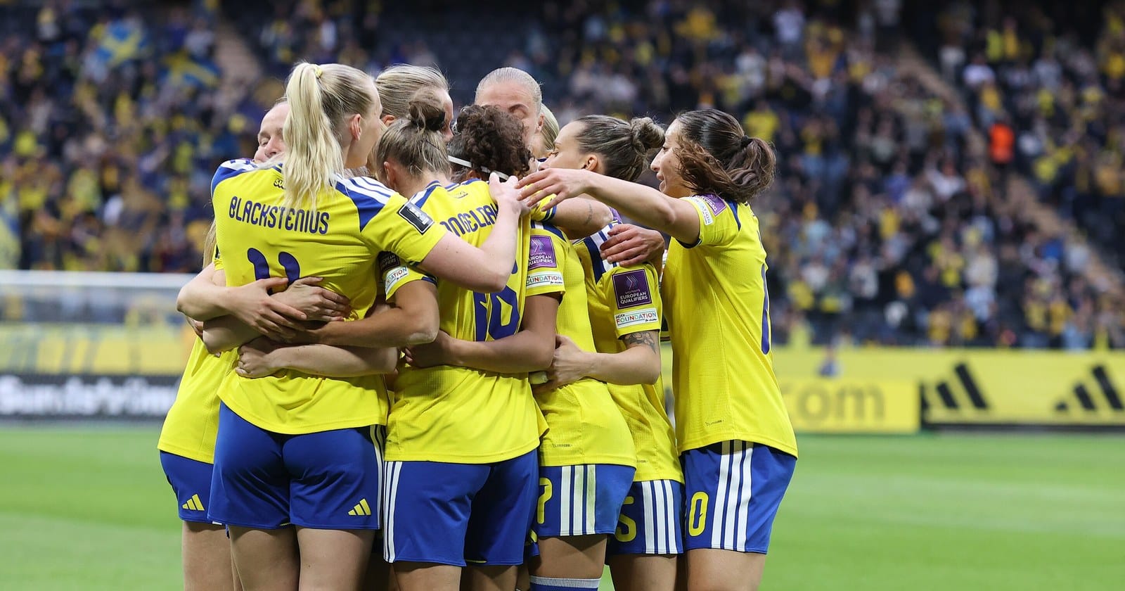 Damlandslaget firar ett mål i gula tröjor inför publiken på Nationalarenan